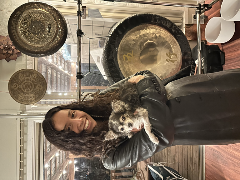Carmina holding small dog with gongs in background